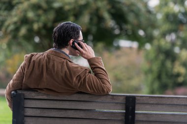 telefon alarak bankta oturan adam