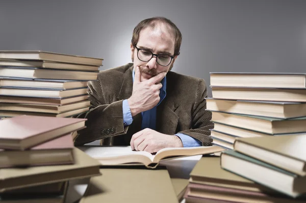 Young professor rounded with stacks of books — Stock Photo, Image