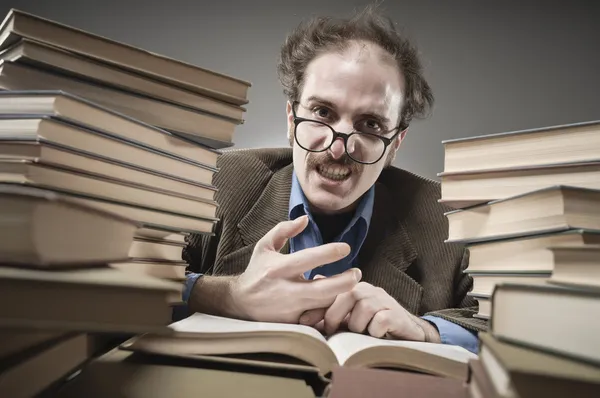 Professeur en colère arrondi avec des piles de livres — Photo