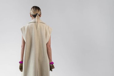 Bej uzun palto ve deri eldiven giyen şık, sarışın bir kadının şık bir yakın çekimi. Klasik çizmeli kız.