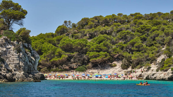 Beautiful sandy beach between rocks and trees in Menorca, Spain