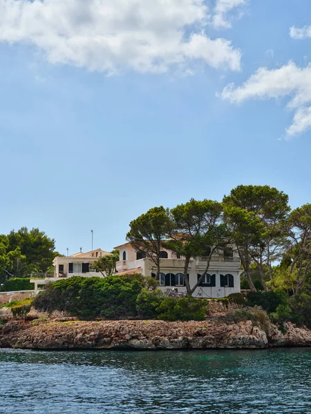 Villa by the sea behind the trees on the rocky coast, Ciutadella, Menorca, Spain