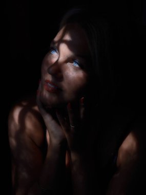 Portrait of a young woman in the dark with partial natural light through the window