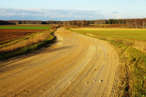 Onverharde weg op herfst achtergrond — Stockfoto