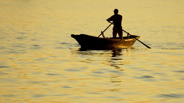 Boot met een man op de achtergrond van de zee bij zonsondergang — Stockfoto