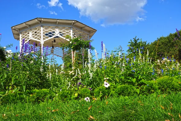 Jardín verde con flores y un mirador blanco — Foto de Stock