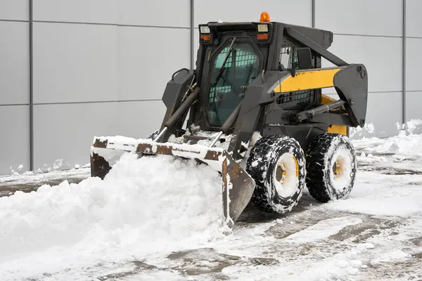 A snowplow tractor clears snow from the house territory. Copy space.