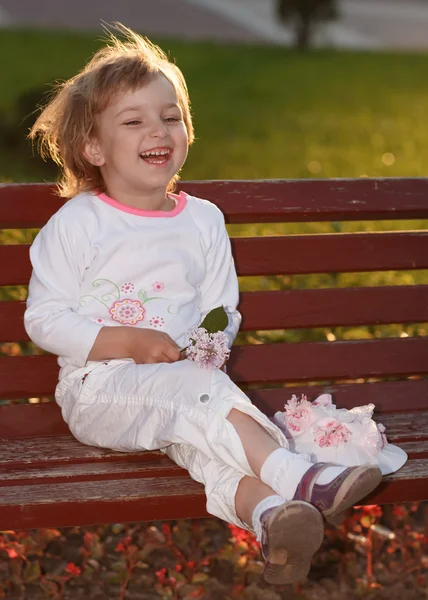 Het meisje in het park op een bankje. — Stockfoto