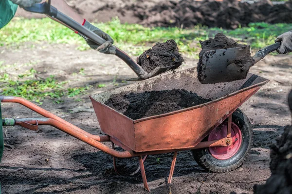 Wheelbarrow in a garden full of soil — Stock Photo, Image