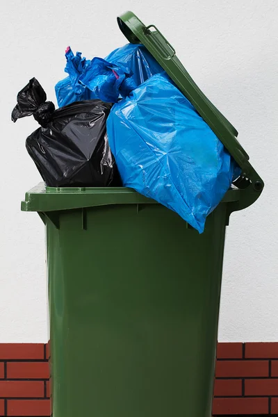Grüne Mülltonne vor weißem Hintergrund mit Plastik — Stockfoto
