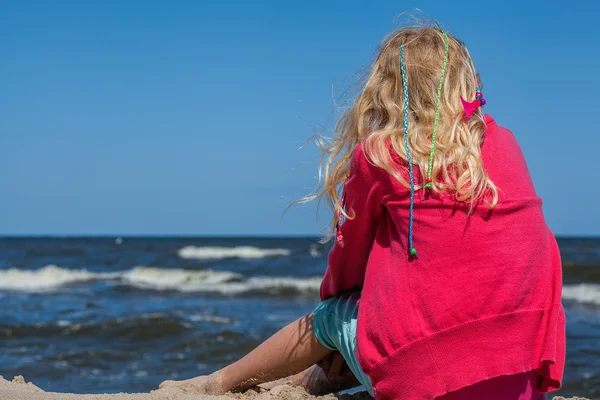 Młoda dziewczyna siedzi na brzegu — Zdjęcie stockowe