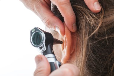 Examining ear with otoscope clipart