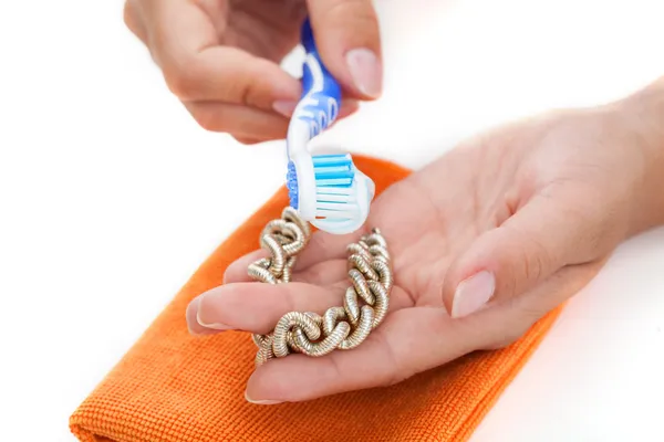 Limpeza pulseira de ouro com uma pasta de dentes — Fotografia de Stock