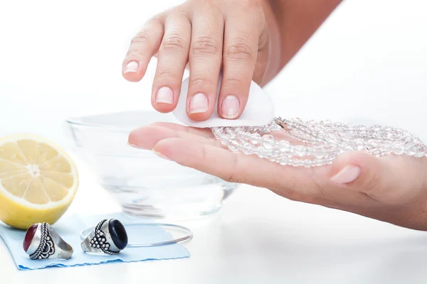 Женские руки чистят ювелирные изделия лимоном — стоковое фото