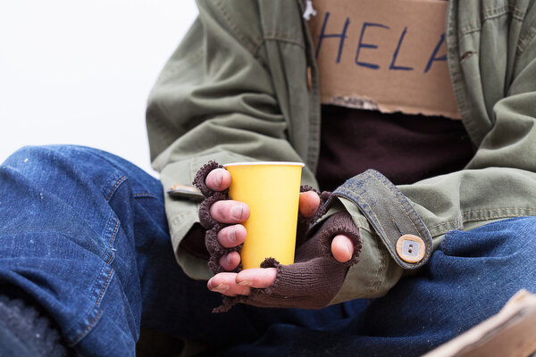 Руки бездомных с бумажной чашкой
