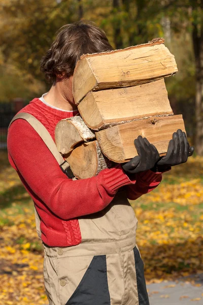 Jeune travailleur tenant une pile de bois de chauffage — Photo