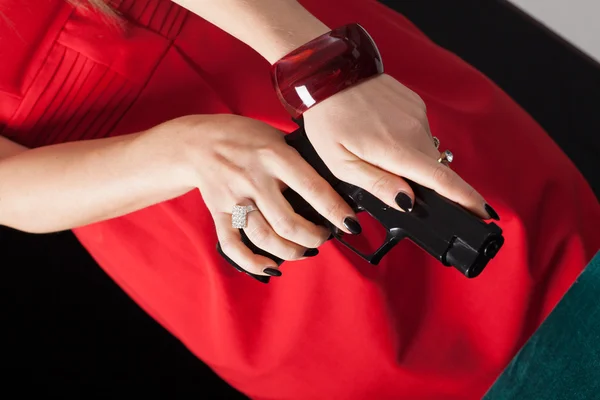 Жінка в червоній сукні перезаряджає пістолет — стокове фото