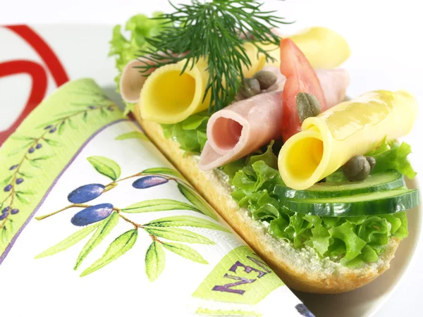 Garnished sandwich on decorative plate and napkin — Stock Photo, Image