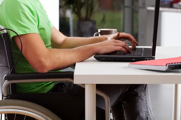 Homem com deficiência escrevendo no laptop — Fotografia de Stock