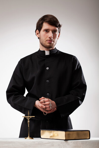 Handsome reverend with crucifix and the Bible