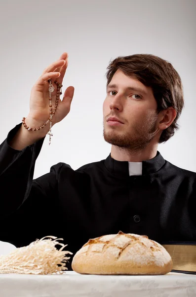 Priester met rozenkrans, brood en de Bijbel — Stockfoto