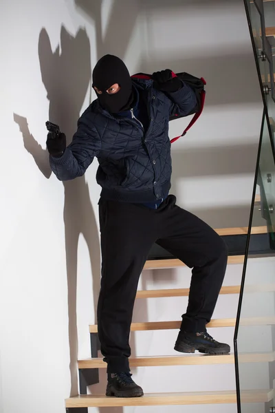 Armed robber on stairs — Stock Photo, Image