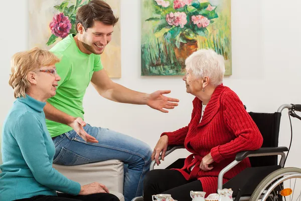 Jonge man tallking met twee oudere vrouwen — Stockfoto