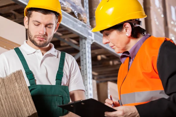 Arbeiter berät sich mit Manager im Lager — Stockfoto