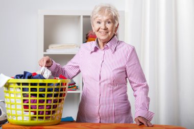 Senior lady during folding laundry clipart