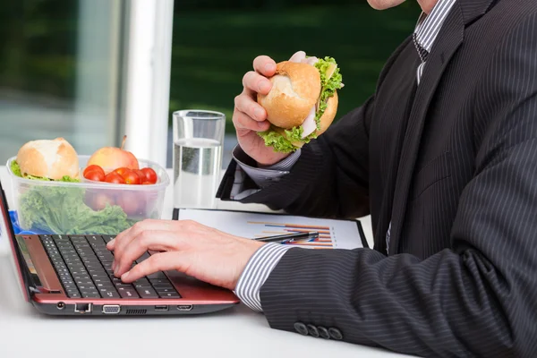 Arbetstagaren äta vid sitt skrivbord — Stockfoto