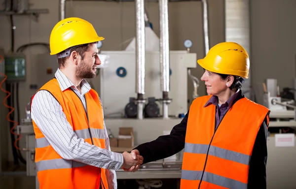 Workers in factory shake hands — Stock Photo, Image