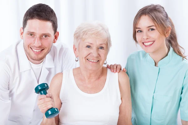 Physiotherapists and exercising elderly woman — Stock Photo, Image