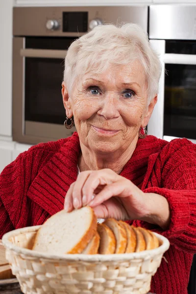 Mulher idosa tomando pão — Fotografia de Stock