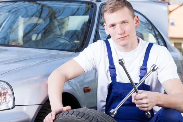 Mechanic with car wheel — Stock Photo, Image