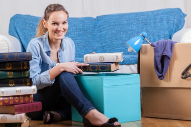 Smiling woman packing books clipart