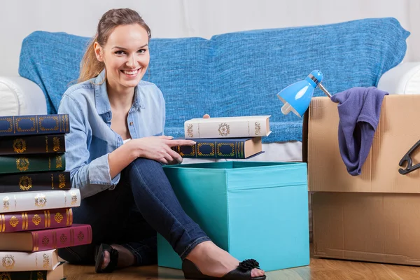 Lachende vrouw verpakking boeken — Stockfoto