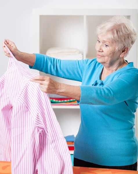 Ältere Frau faltet Hemd — Stockfoto