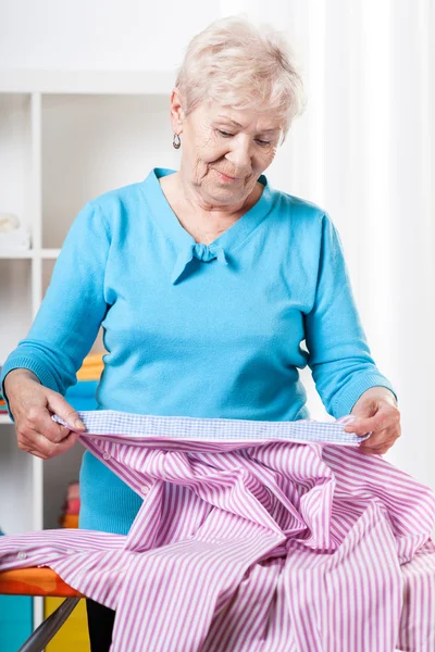 Mulher idosa preparando camisa para passar a ferro — Fotografia de Stock