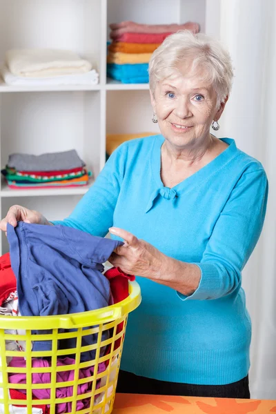 Mujer mayor clasificando ropa sucia — Foto de Stock