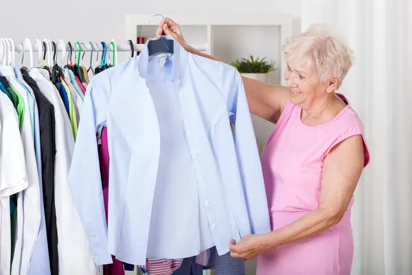 Mulher idosa escolhendo uma roupa — Fotografia de Stock