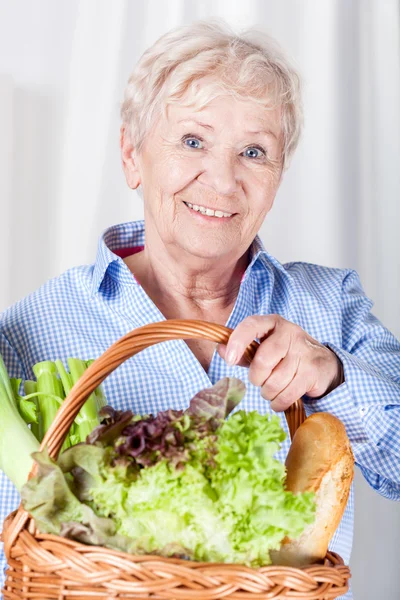 Elderly woman holding basket — Stock Photo, Image