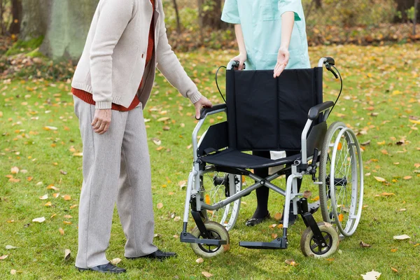 Discapacitados tratando de sentarse en silla de ruedas — Foto de Stock