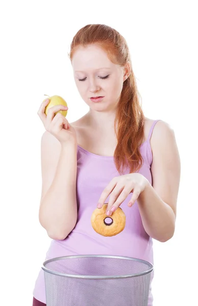 Girl choosing apple instead of a doughnut — Stock Photo, Image