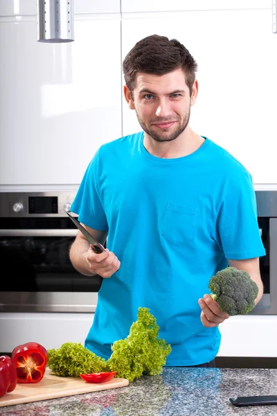 Uomo con broccoli e coltello in mano — Foto Stock