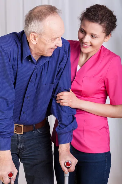 Mann auf Krücken und seine Krankenschwester — Stockfoto