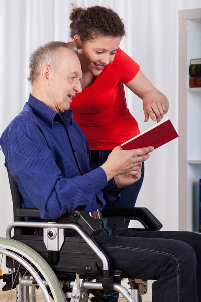 Enfermera y hombre discapacitado leyendo libro — Foto de Stock