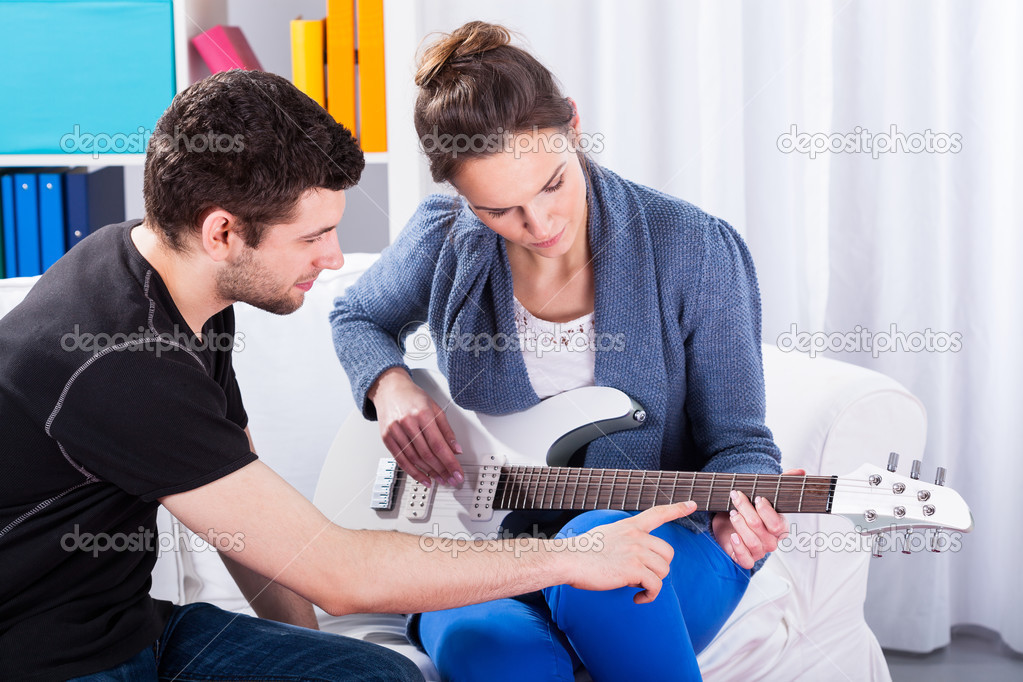 Musician teaching his girlfriend playing guitar