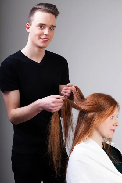 Coiffeur peigne les cheveux du client — Photo