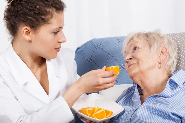 Enfermeira alimentando mulher idosa — Fotografia de Stock