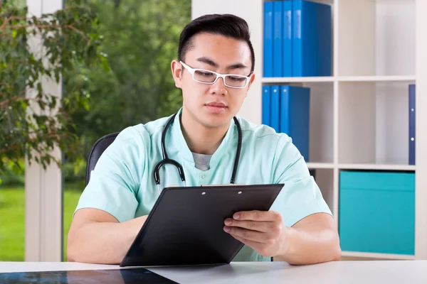 Asian doctor filling documents — Stock Photo, Image